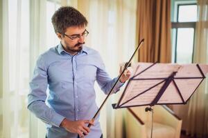 Man playing violin at home. He rosin a violin bow. photo