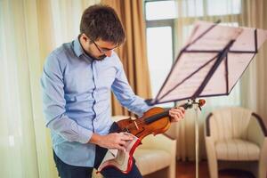 hombre jugando violín a hogar. él es limpieza su instrumento. foto