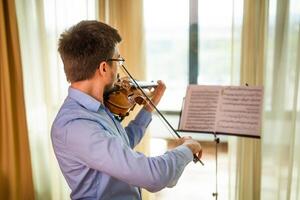 Man playing violin at home. He is practicing for live performance. photo