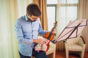 hombre jugando violín a hogar. él es limpieza su instrumento. foto