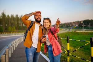 Happy smiling couple are using maps on smartphone in the city. Tourists are sightseeing in the city. photo