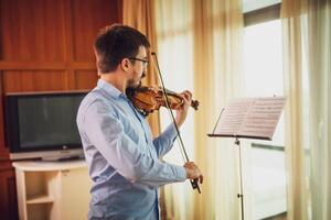 Man playing violin at home. He is cleaning his instrument. photo