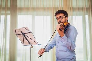 Man playing violin at home. He is cleaning his instrument. photo