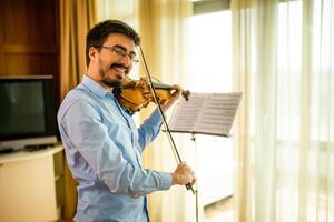 Man playing violin at home. He is cleaning his instrument. photo