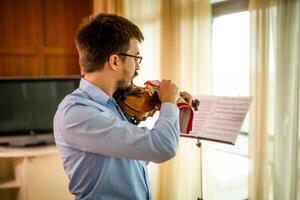 hombre jugando violín a hogar. él es limpieza su instrumento. foto