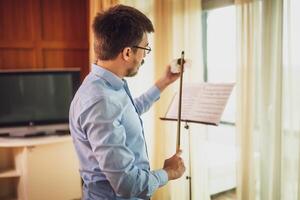 Man playing violin at home. He is cleaning his instrument. photo