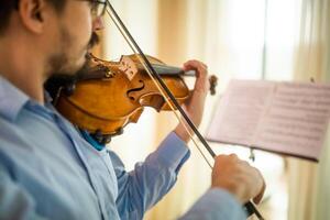 hombre jugando violín a hogar. él es limpieza su instrumento. foto