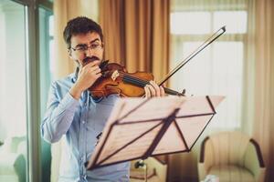 hombre jugando violín a hogar. él es limpieza su instrumento. foto