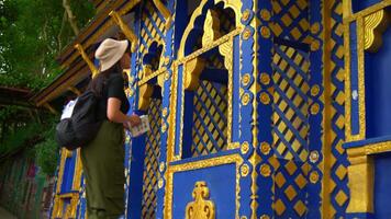 Traveler admiring intricate blue and gold patterns on a temple wall in Southeast Asia. video