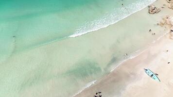 aereo superiore Visualizza di pesca barca attraccato di tropicale costa, giustapposti con vivace scena di turisti godendo cristallino turchese acque. con camera per testo. dominicano, macao spiaggia. minimalismo video