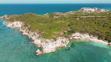 Area view of rocky peninsula covered in greenery washed by turquoise waters of Caribbean Sea on bright sunny day. Drone is moving along a circular trajectory video