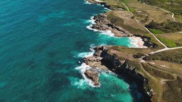 zona panorámico ver de vibrante Oceano aguas arremolinándose alrededor pintoresco rocoso línea costera, con olas estrellarse en contra rocas a macao playa en dominicano república. zumbido vista. video