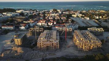 Antenne Aussicht von laufend Konstruktion von luxuriös direkt am Strand Resort im punta Kana, dominikanisch Republik, mit groß Turm Kran, Bagger und Sand beim Arbeit gegen Hintergrund von Sonnenuntergang. noval video