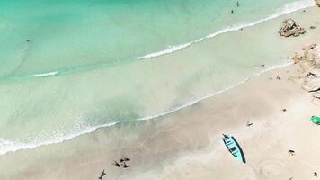 Antenne oben Aussicht von Angeln Boot links verlassen auf tropisch Küstenlinie, während Touristen genießen Schwimmen im kristallklar Türkis Gewässer. Minimalismus. Hintergrund. Raum zum Text. Abstraktion. video