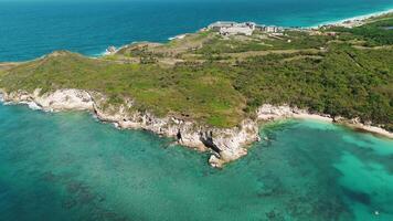 Amazing aerial view. rocky coastline against backdrop of bright sunny day. Turquoise waters, lush green vegetation on rocks. This place, of volcanic origin. Drone is moving along a circular trajectory video