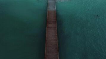 Aerial cinematic view of pier, tourist beach and resort at dusk, cold lighting video