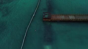 Drone is monitoring pier circling it to left in turquoise Caribbean Sea at dusk video