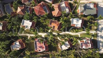 Aerial top view of tourist condominium, sandy beach dotted with beach umbrellas, set against stunning Caribbean Sea sunset backdrop. This scene transitions smoothly from beach houses to tranquil sea video