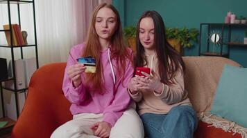 allegro ragazze amici utilizzando credito banca carta e smartphone mentre trasferimento i soldi, acquisti video