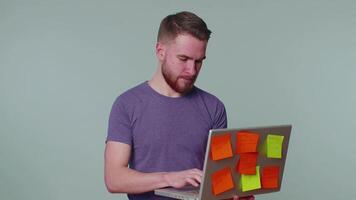 Exhausted man freelancer with pasted sticker notes using laptop computer, concentration problem video