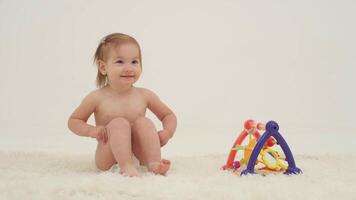 Happy little girl in diaper is playing toys video