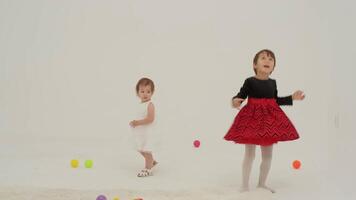 Toddler girl wearing diaper and her sister playing with balls video