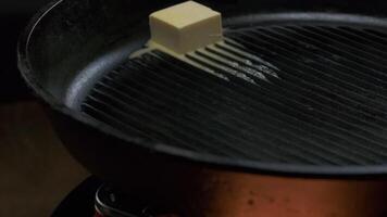 a piece of butter is melted in a frying pan, close up video