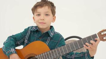 pequeño chico es jugando grande clásico guitarra sentado en el taburete video