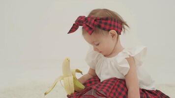 Little girl in plaid headband is holding banana video