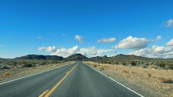 Desert Highway Stretching into the Distance, A vast open road slicing through the desert landscape under a bright blue sky. video