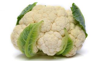 Whole head of the fresh raw cauliflower with some leaves close-up on a white background photo