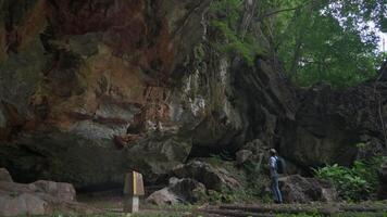 solo femelle géologue est explorant le rocheux mur de une grand Montagne la grotte dans le été. prendre Remarque géologique Les données à étude le mouvement de la terre croûte. video