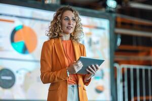 A confident business woman stands on stage, poised and ready to deliver her presentation at a conference. . photo