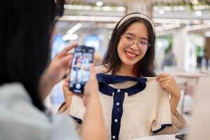 un mujer tomando un imagen de su amigo con un nuevo vestir, teniendo un divertido compras día juntos. foto