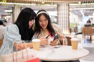 Two happy young Asian female friends are hanging out together at the shopping mall on the weekend. photo