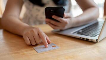 un de cerca imagen de un asiático mujer señalando su dedo a un crédito tarjeta en el mesa. foto