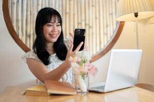 A cheerful young Asian woman is talking on a call on her smartphone with her friend. photo