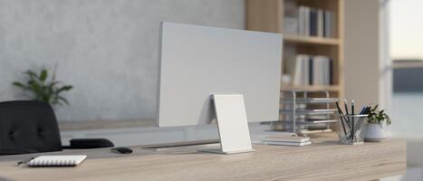 The interior design of a contemporary white home office features a computer on a wooden desk. photo