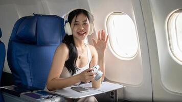 A cheerful female is waving her hand at the camera, traveling for her summer vacation by plane. photo