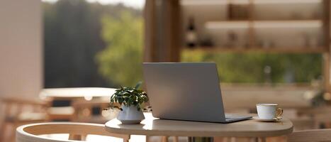 A laptop and a coffee cup on a wooden table in a beautiful minimalist restaurant or coffee shop. photo