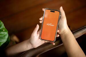 Payoneer logo on an iPhone14 screen, a woman using the Payoneer application on her smartphone. photo