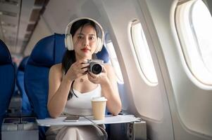A beautiful Asian female passenger is taking pictures with her camera during the flight. photo