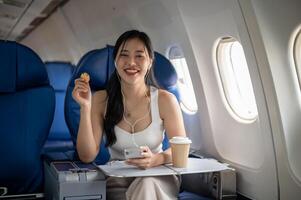 A female passenger is enjoying snacks and listening to music on her headphones during the flight. photo