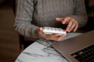 A cropped shot of a woman working at a table indoors, using a calculator. accounting, financial photo