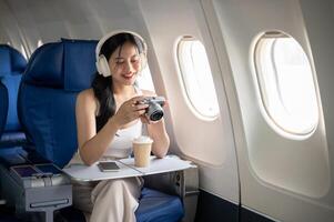 A female passenger is checking pictures on her camera during the flight of her summer vacation. photo