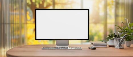 A computer mockup on a desk in a modern home office with a large window with a beautiful garden view photo