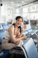 An attractive Asian female traveler passenger is sitting in the airport terminal, travel by plane. photo