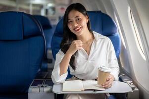 A beautiful Asian businesswoman seated at a window seat on a plane, traveling for a business trip. photo