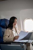 An attractive Asian businesswoman is preparing her report during the flight for her business trip. photo