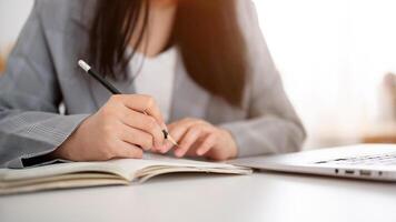 A cropped shot of a businesswoman focused on writing or taking notes in the notebook with a pencil. photo